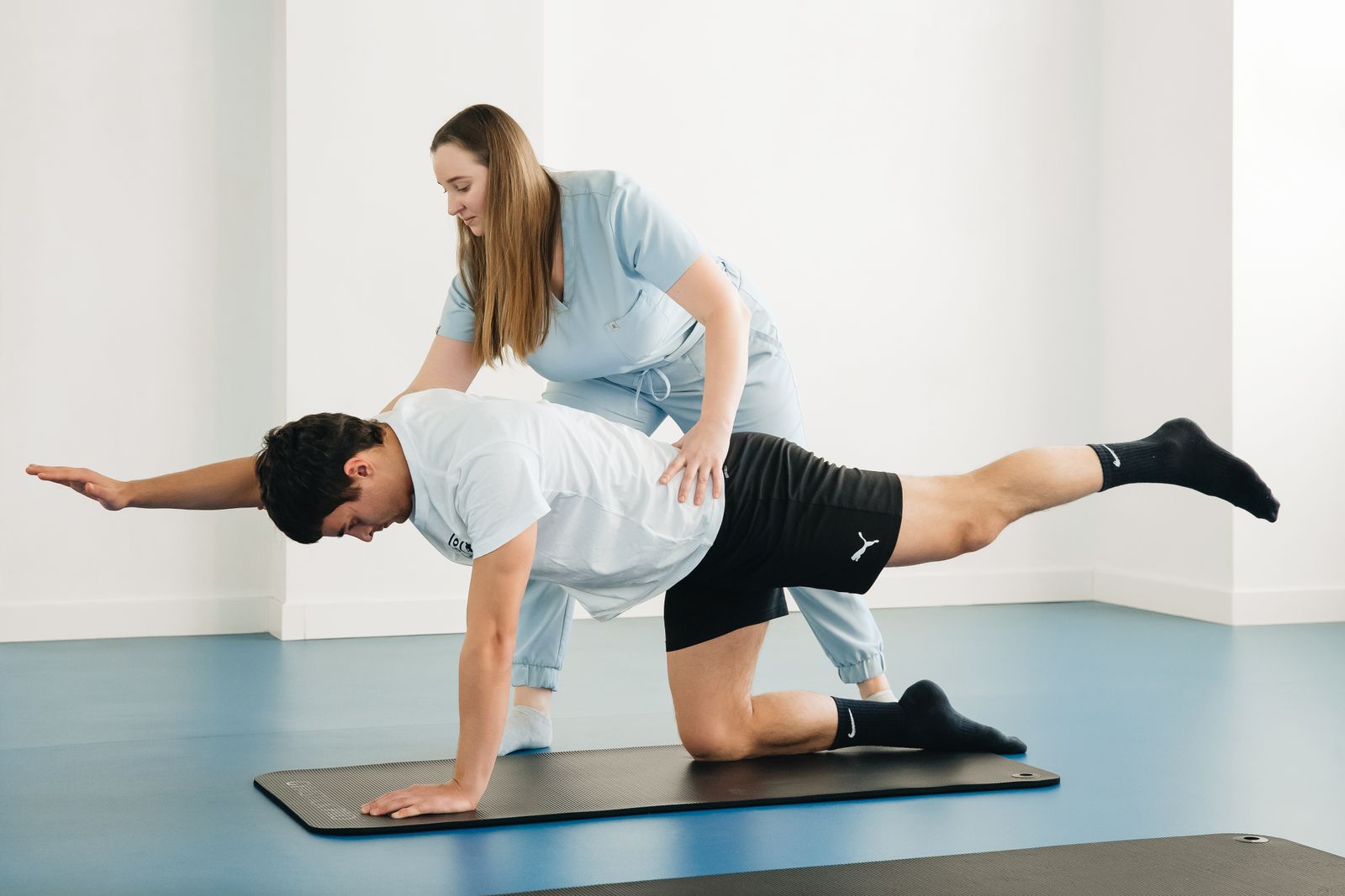 Physiotherapist guiding a patient through a core stability exercise on a mat