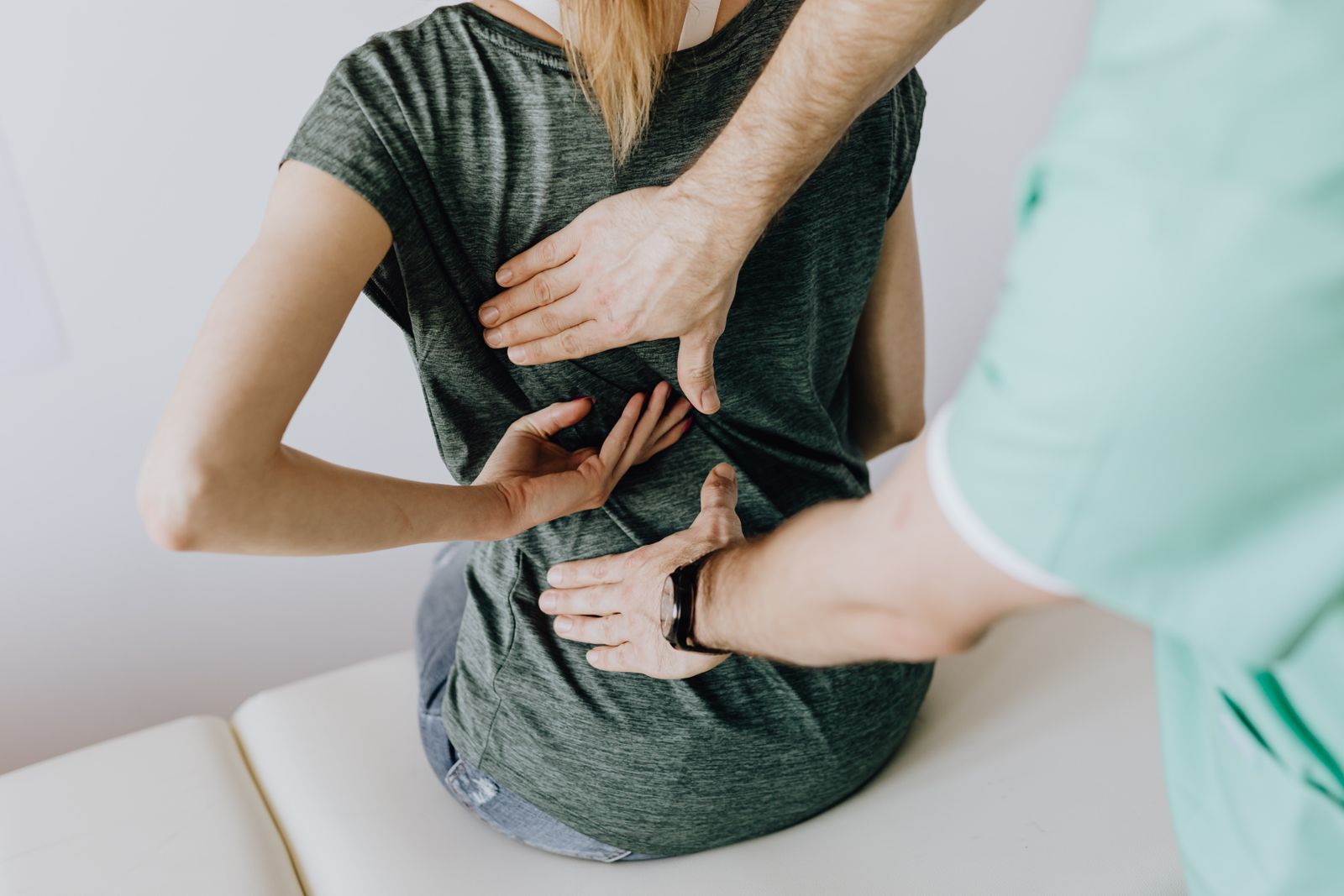 Physiotherapist assessing a patient's lower back and spine alignment during a clinical exam